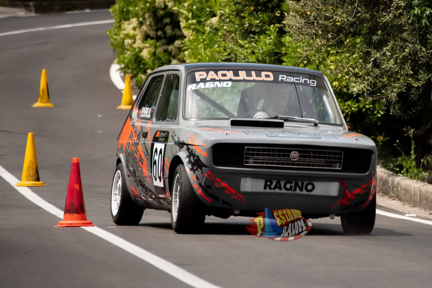 Fiat 127 numero 60 di Paolillo Racing che passa a filo dei birilli gialli e rossi allineati sull'asfalto.